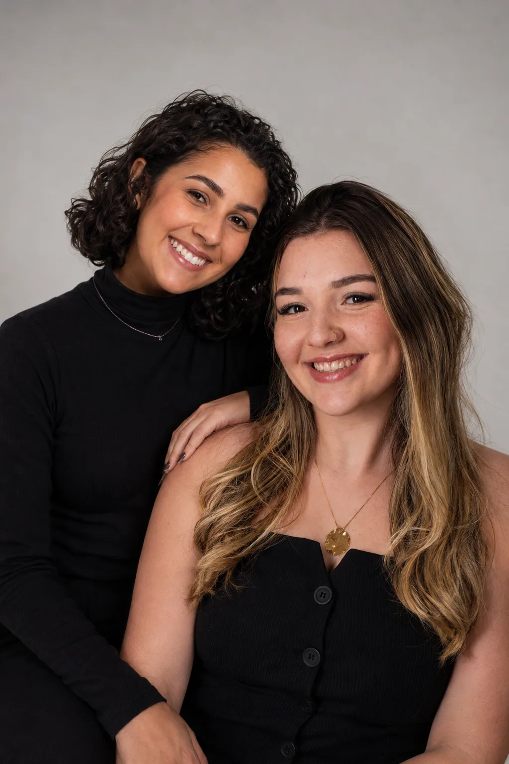 Sol e Júlia, as duas profissionais do JS Studio, sorrindo juntas em um retrato de estúdio
